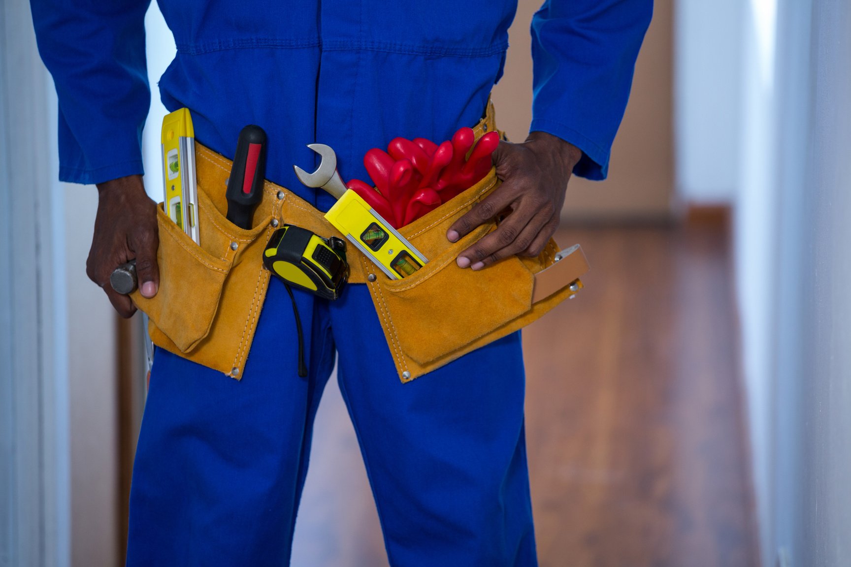 Mid section of handy man wearing tool belt